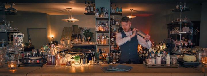 Le Verre à Monique, Genève : barman préparant un cocktail derrière le bar aux bougies